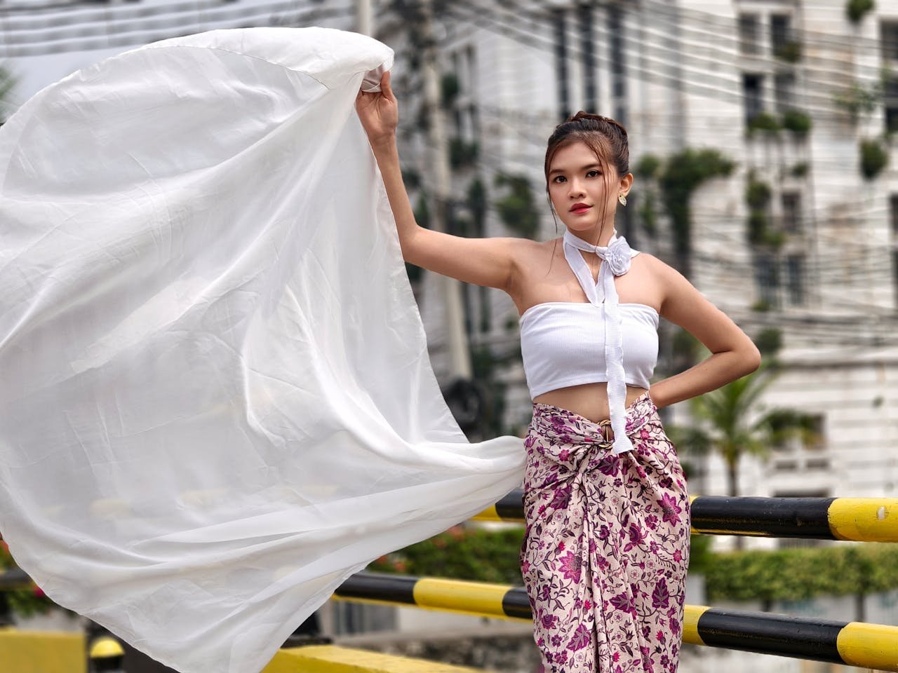 A woman in traditional Indonesian dress elegantly holds flowing white fabric in Jakarta, Indonesia.
